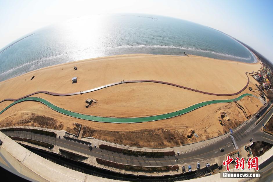 3月13日，秦皇島萬米臨海沙灘木棧道。據(jù)了解，該木棧道全長約4200米，與北戴河區(qū)原有的7500米木棧道對接后全線總長度1.17萬米，整個(gè)木棧道東起秦皇島體育基地游船碼頭，西至北戴河濕地公園，呈波浪形蜿蜒10.4公里海岸線。 中新社發(fā) 曹建雄 攝 CNSPHOTO